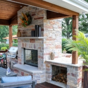 custom outdoor room fireplace with a built in grill and wood shelf