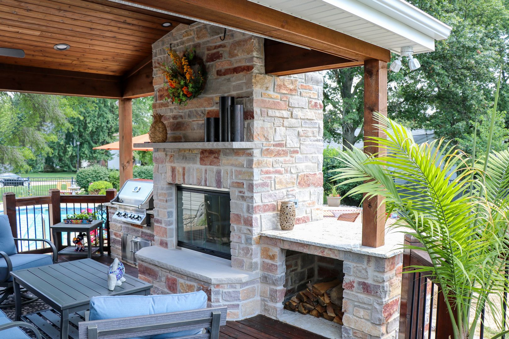 custom outdoor room fireplace with a built in grill and wood shelf