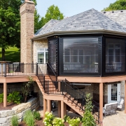 A unique screen room on a composite deck. The patio level includes an underdeck system and InfraTech heaters. The screen room includes Universal Motions retractable Vinyl walls.