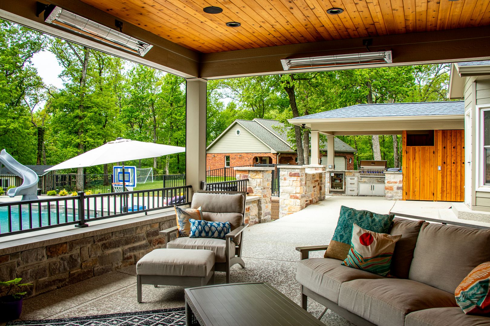 A custom and unique outdoor space that includes two sections of a covered patio. This section includes an InfraTech Heater add on to assist the stone fireplace.