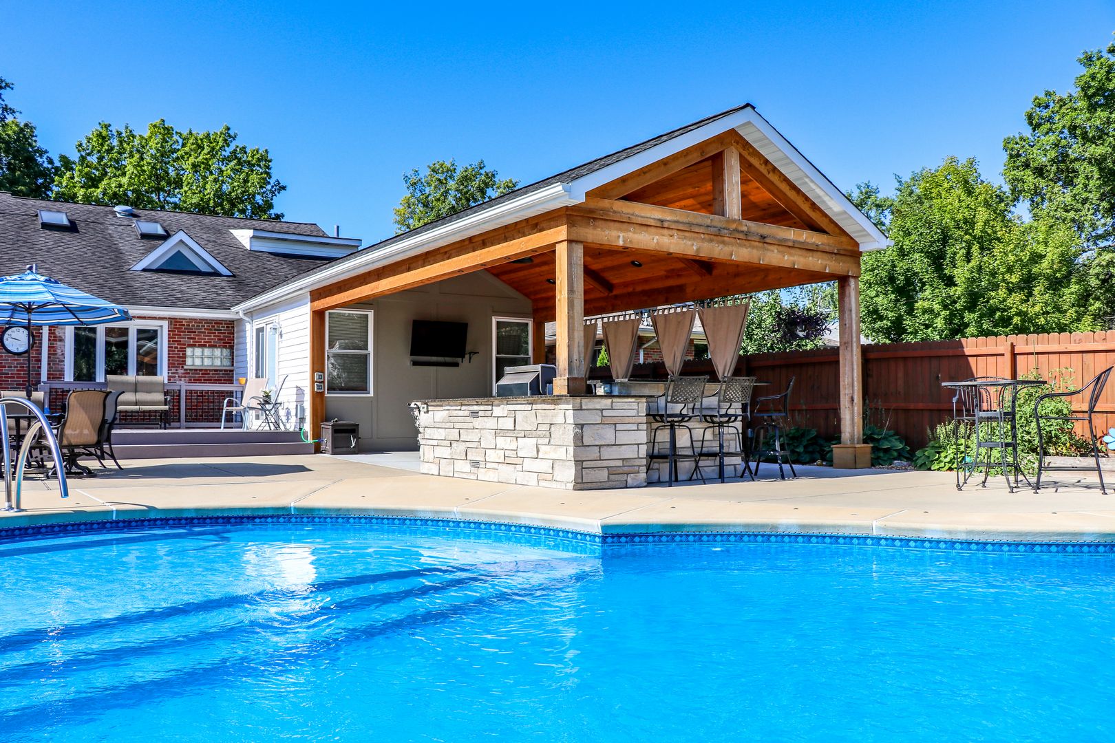 pool side outdoor room with an outdoor kitchen feature that has seating for up to five people