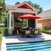 Pool side outdoor room with a beautiful fireplace feature and stone wall in the back