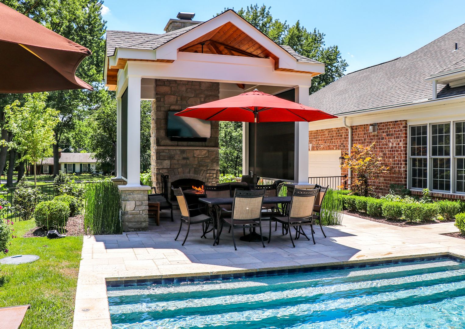 Pool side outdoor room with a beautiful fireplace feature and stone wall in the back