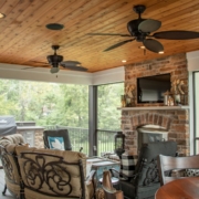 Outdoor screen room deck with a fireplace, wood ceilings, and an outdoor grilling and beverage center