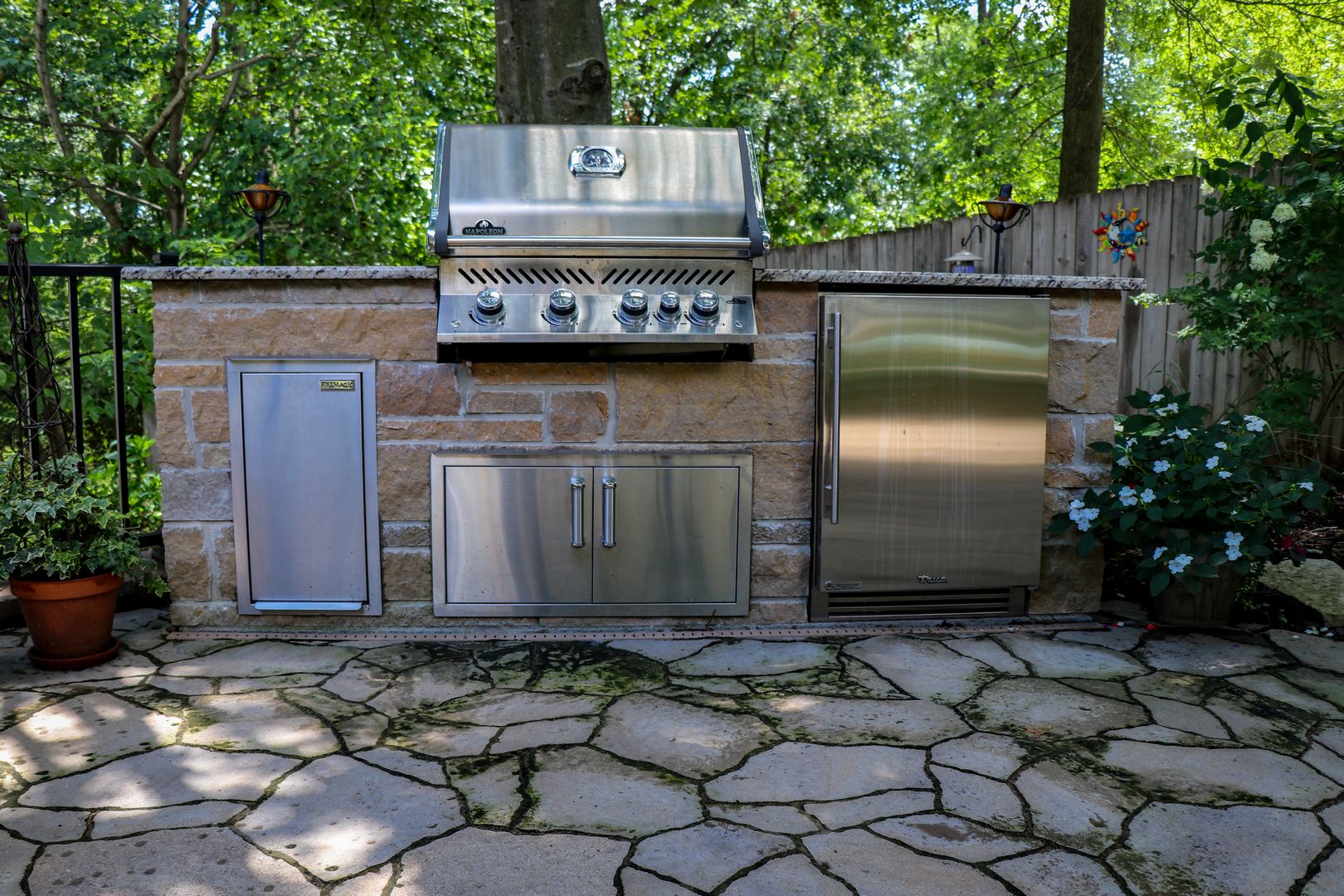 A grilling and beverage center located on a stone patio